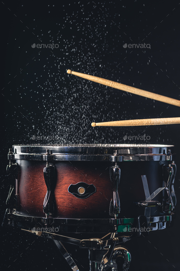 Drummer using drum sticks hitting snare drum with splashing water
